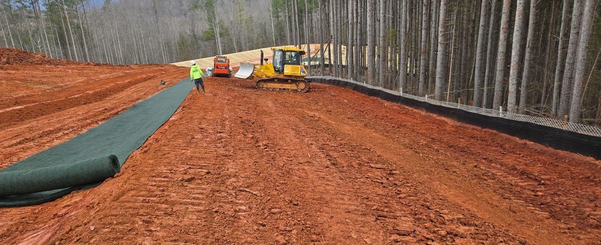 Crew installing erosion-control matting beside a graded access route