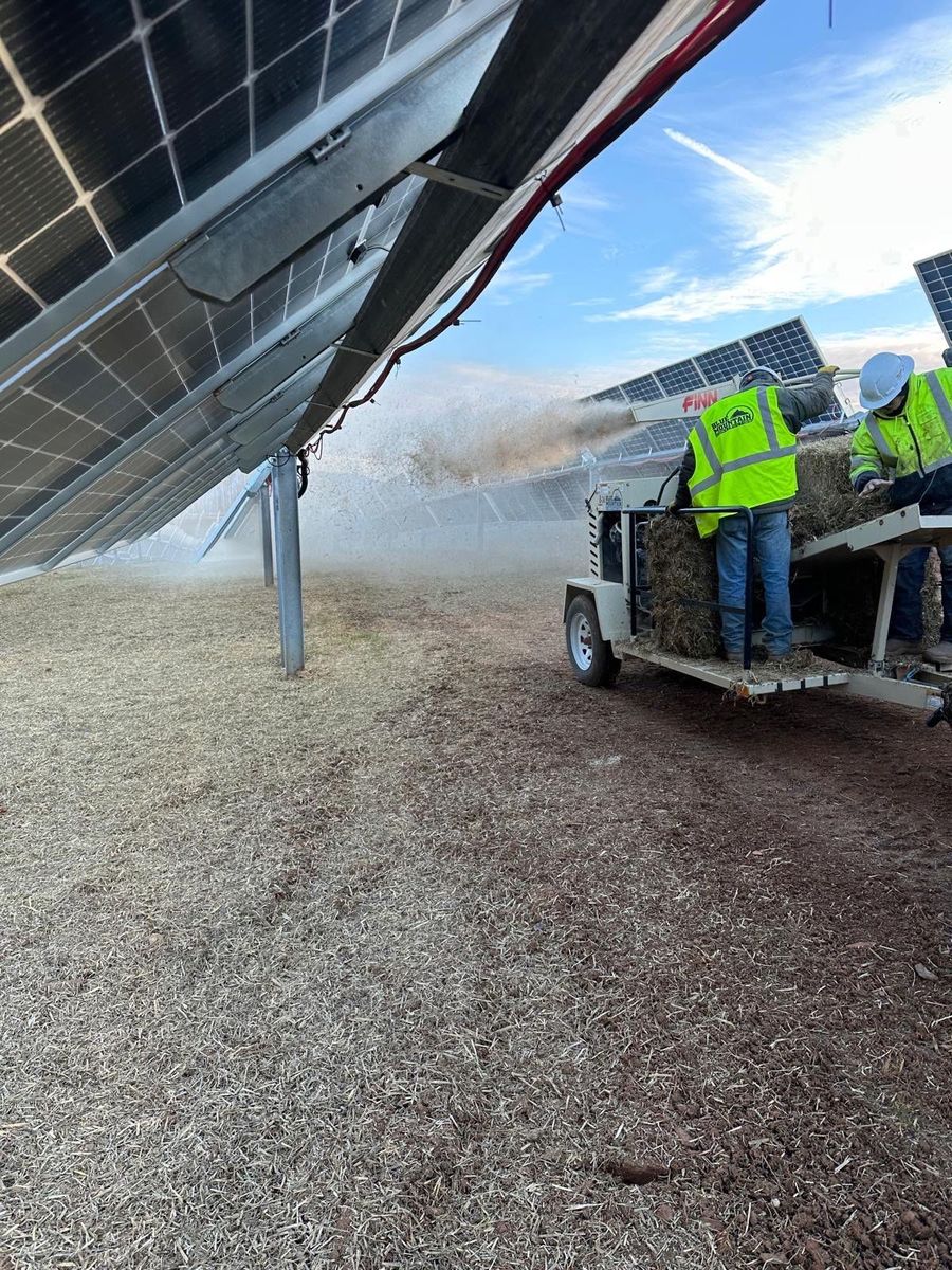 Crew stabilizing exposed soil beneath solar panel rows