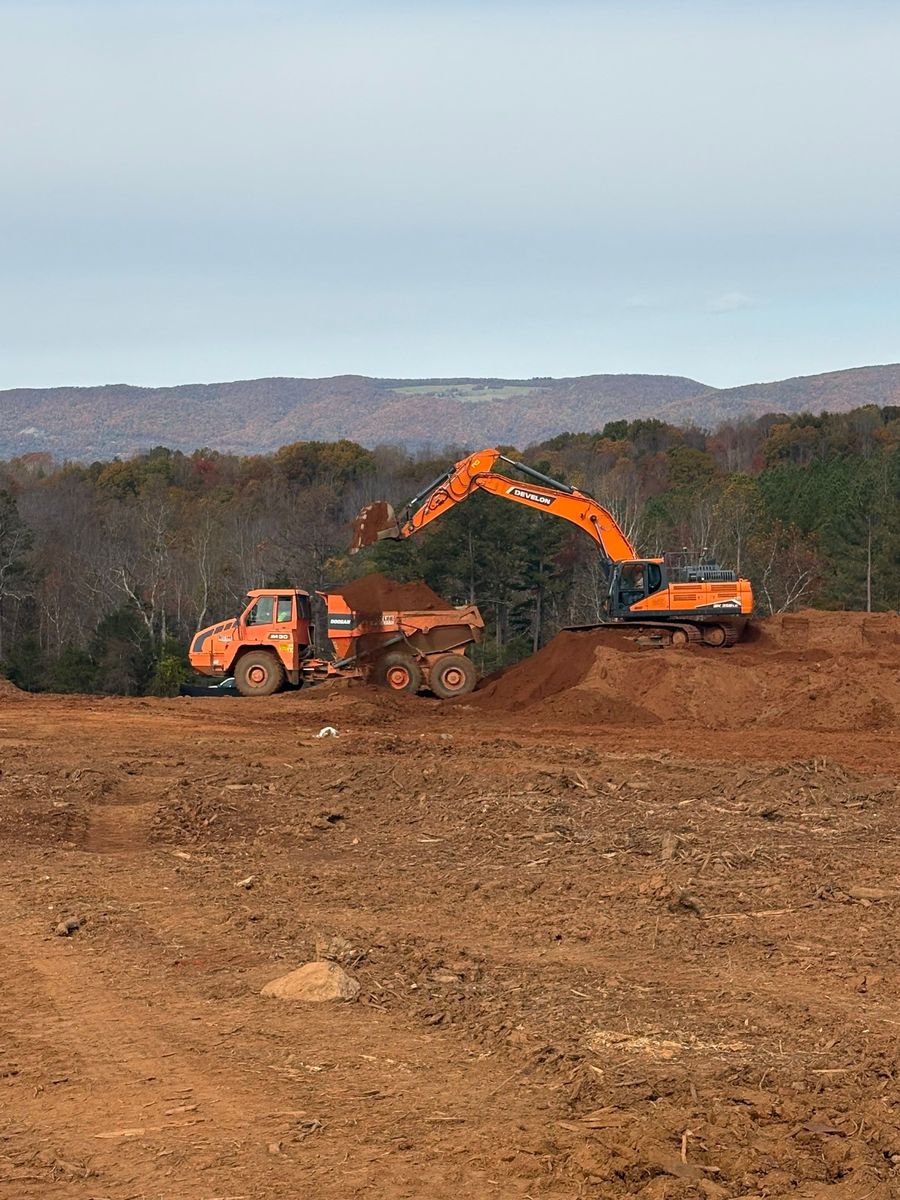 Excavator loading an articulated dump truck during grading work