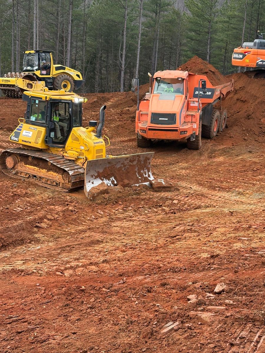 Dozer, excavator, and haul truck working together on site grading