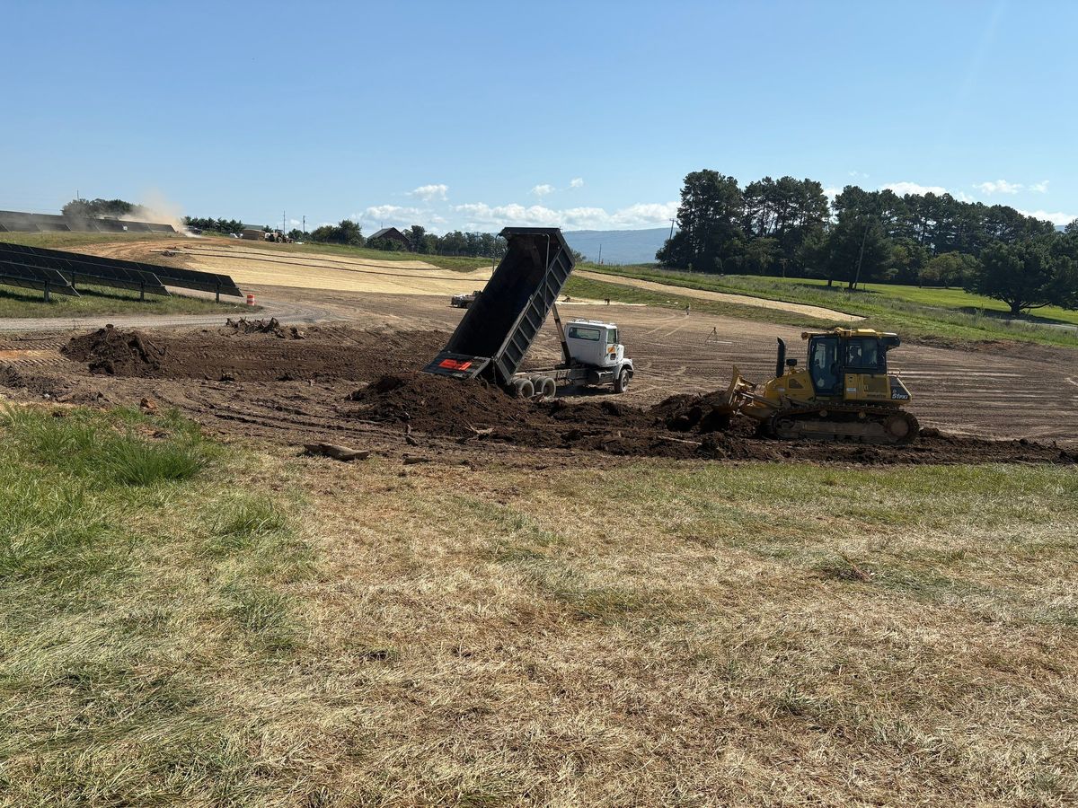 Dump truck and dozer moving soil across a utility-scale solar site