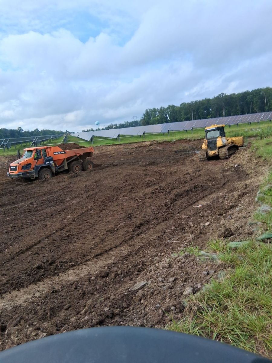 Excavator and dozer grading an active utility-scale solar site