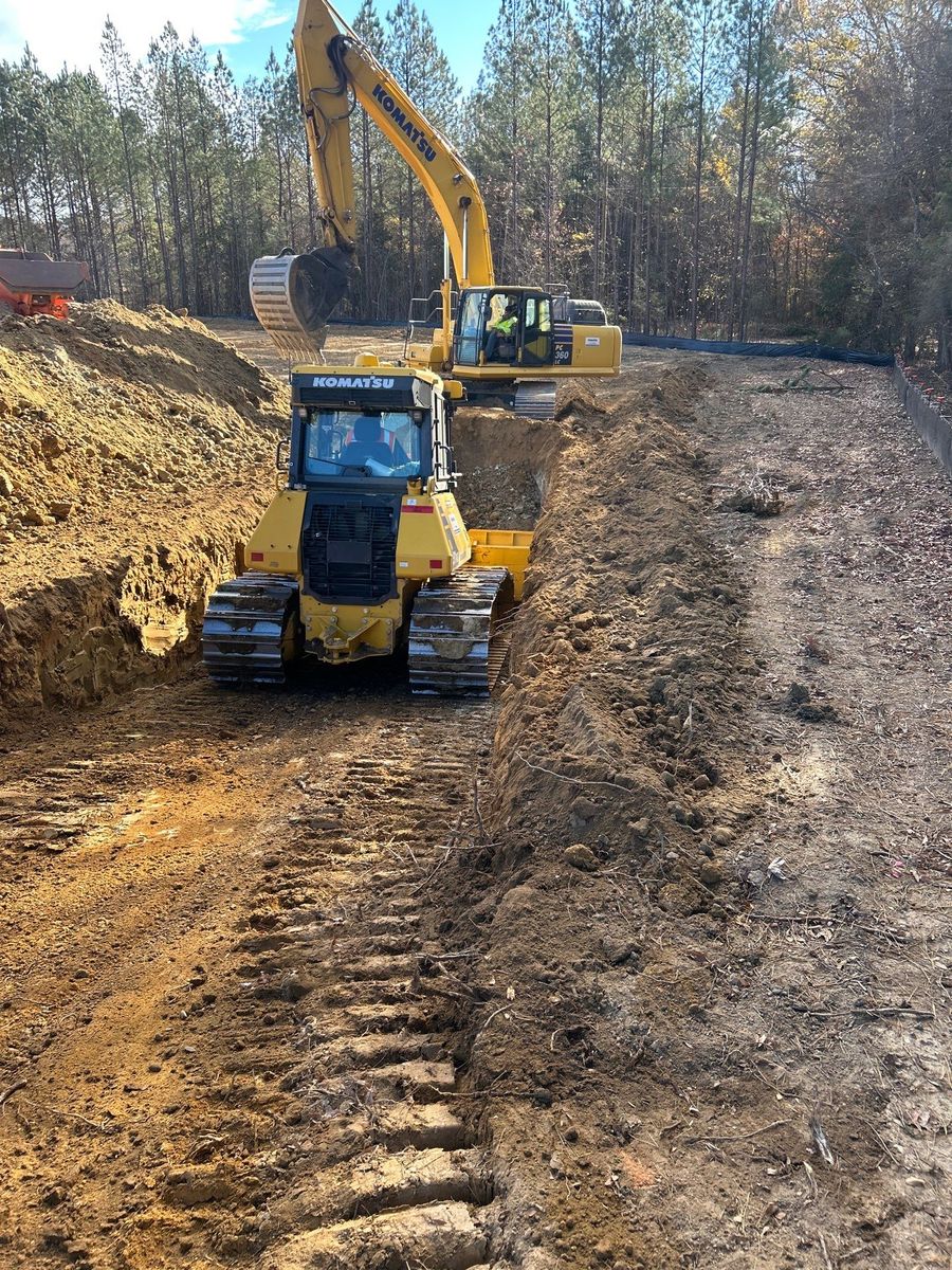 Excavator and compact track loader completing site work along a solar field