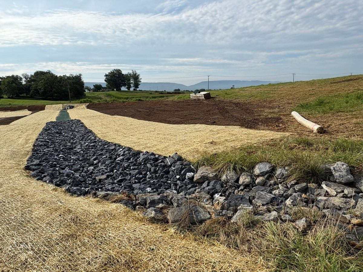 Rock-lined channel and erosion control matting with mountain backdrop
